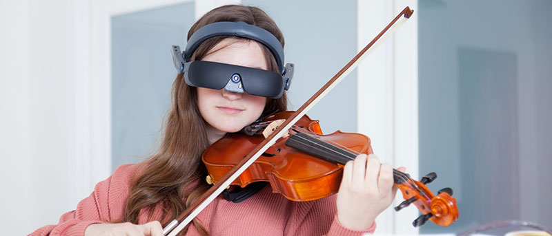 Jeune fille utilisant l'eSight en jouant du violon